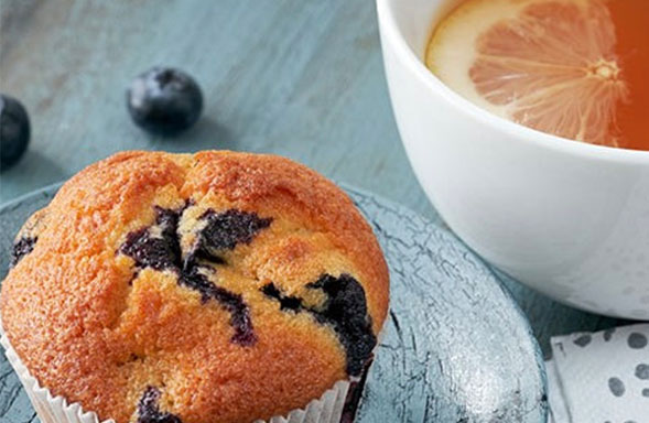 A blueberry muffin with a beverage